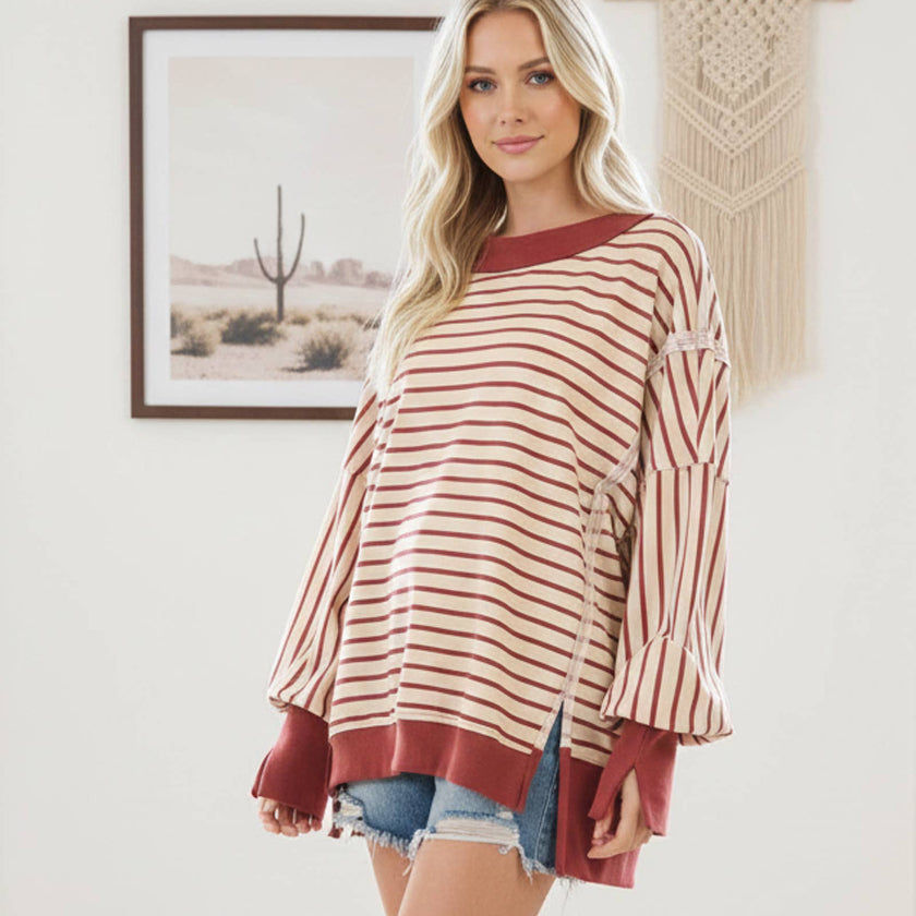 Woman wearing a striped sweater and denim shorts in a room with a painting on the wall.