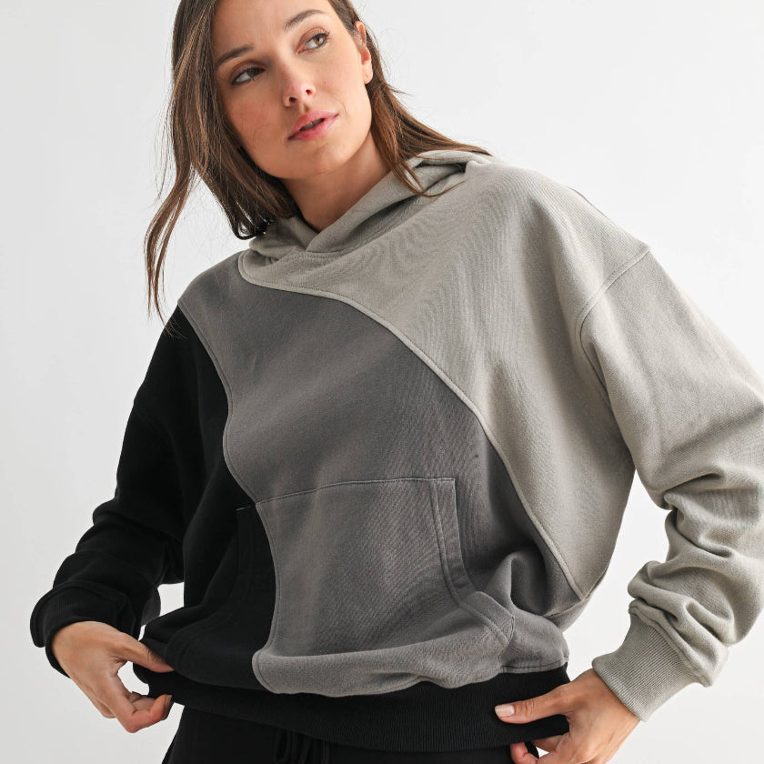 Woman wearing a gray and black color-blocked hoodie on a white background
