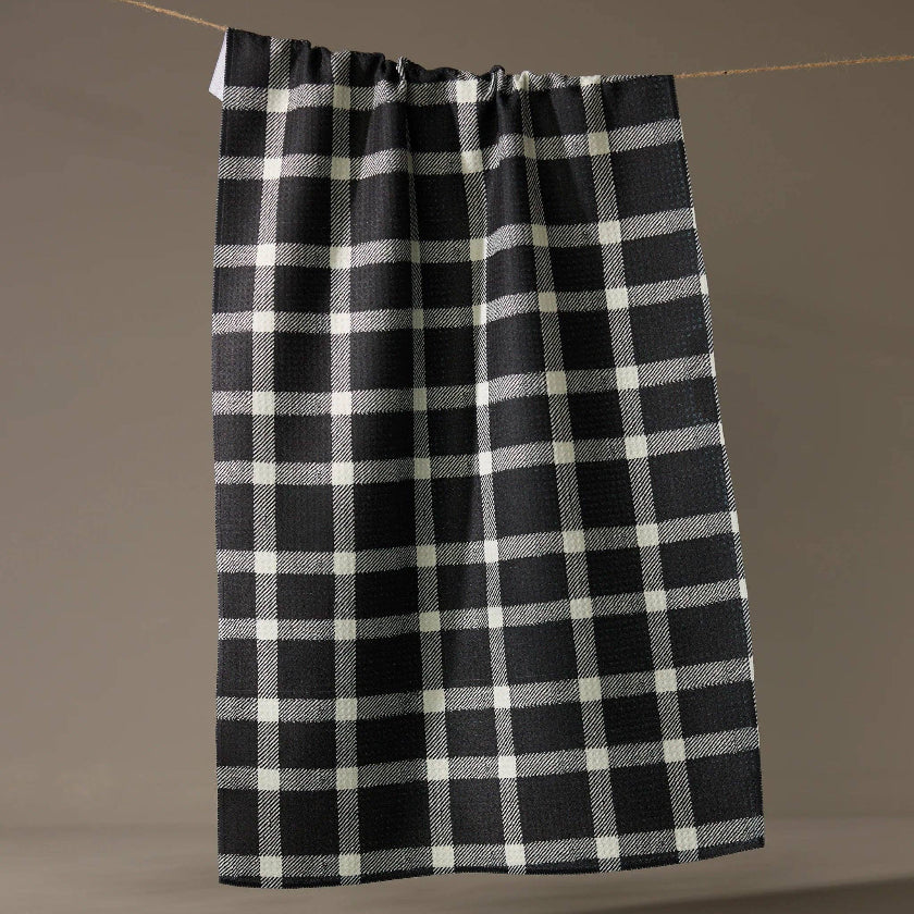 Black and white checkered towel hanging on a line against a brown background