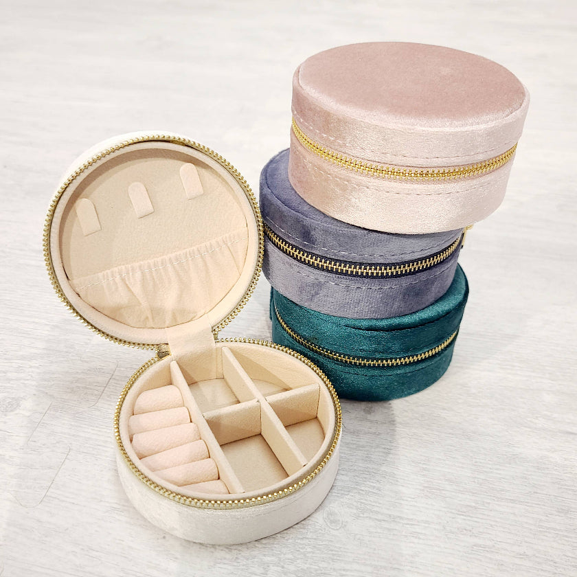 Set of round jewelry boxes with compartments and a stack of similar boxes on a light background