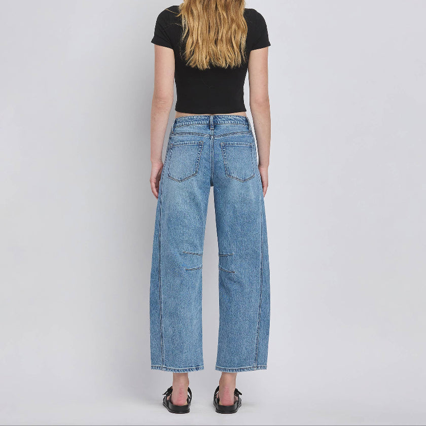 Person wearing blue jeans and a black top on a plain background