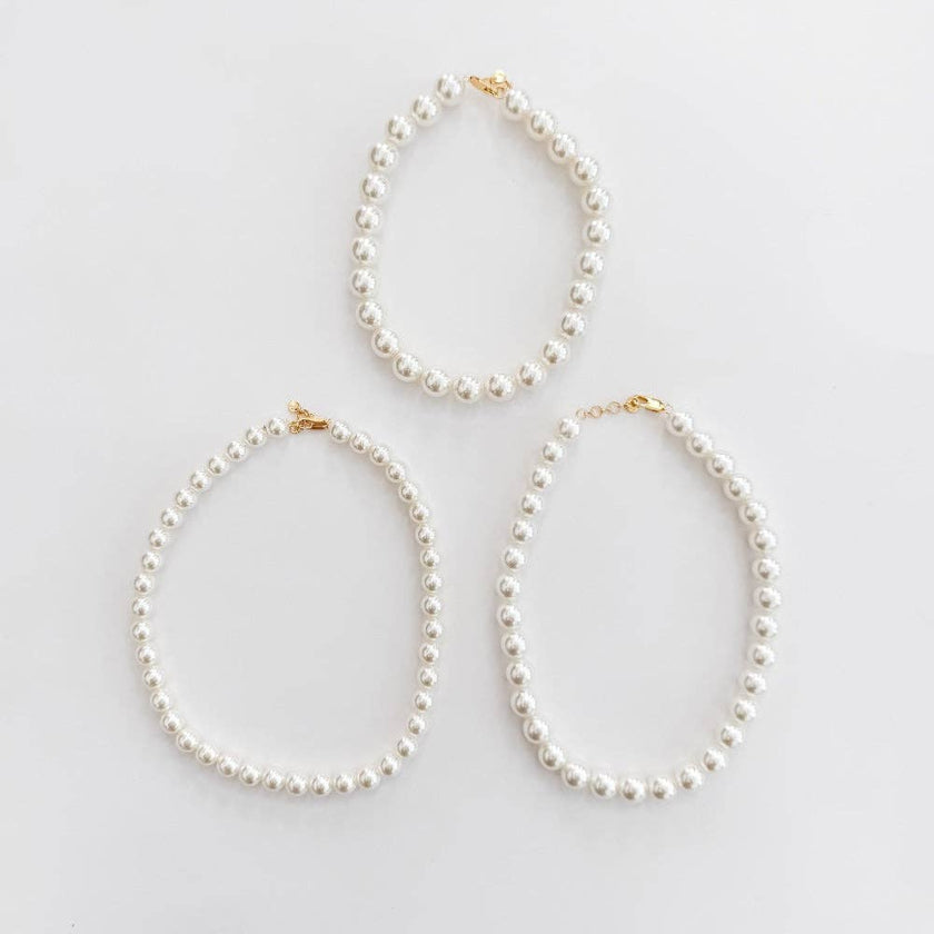 Three pearl necklaces on a light gray background