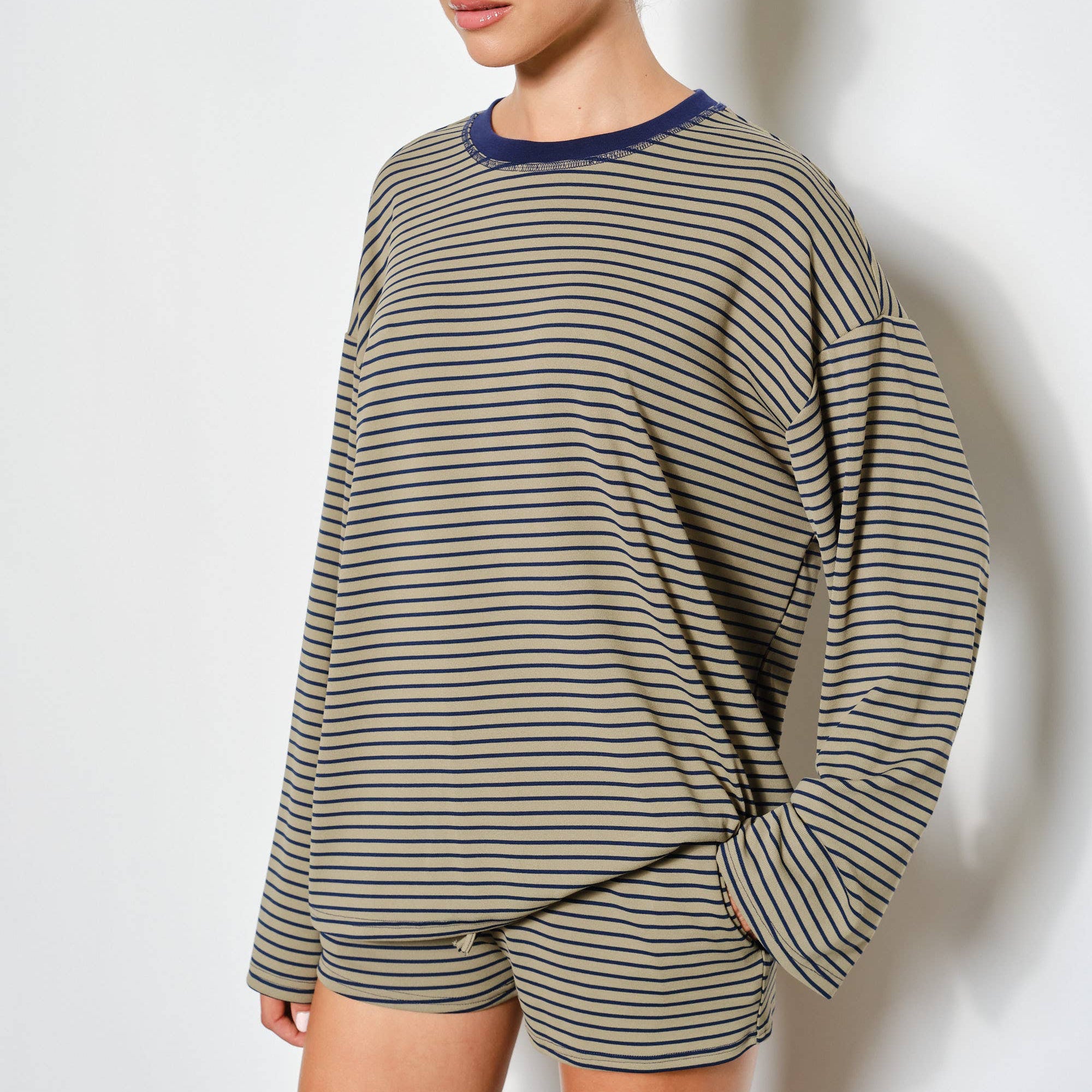 Woman wearing a striped long-sleeve top and shorts on a white background