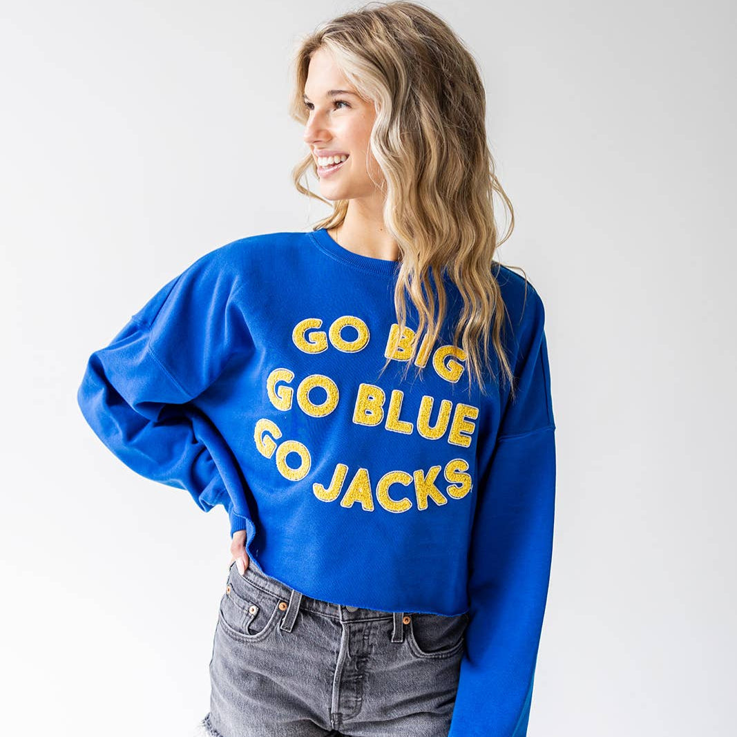 Woman wearing a blue sweatshirt with 'GO BIG GO BLUE GO JACKS' text on a white background