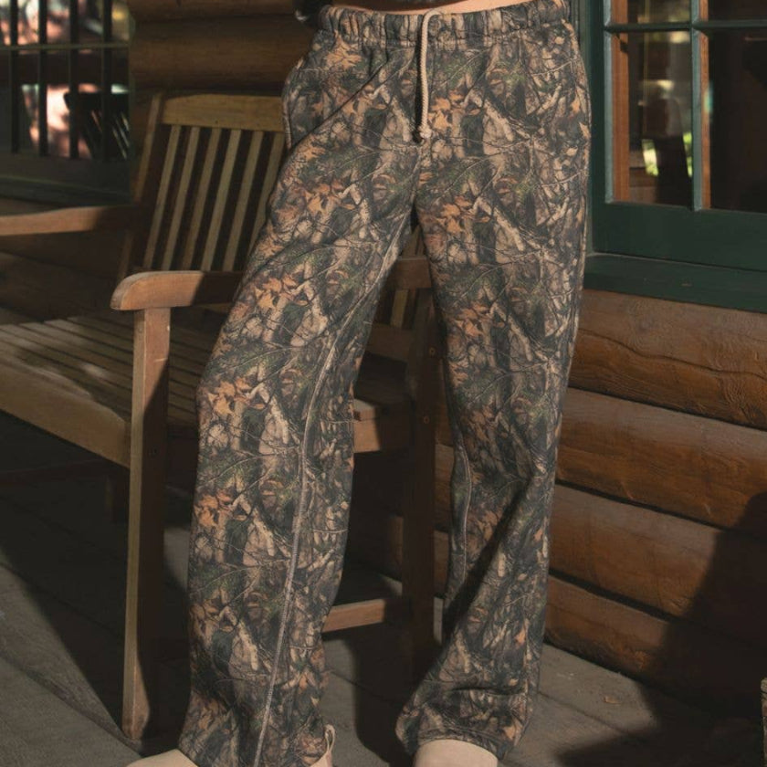 Person wearing a camouflage outfit standing on a wooden deck.