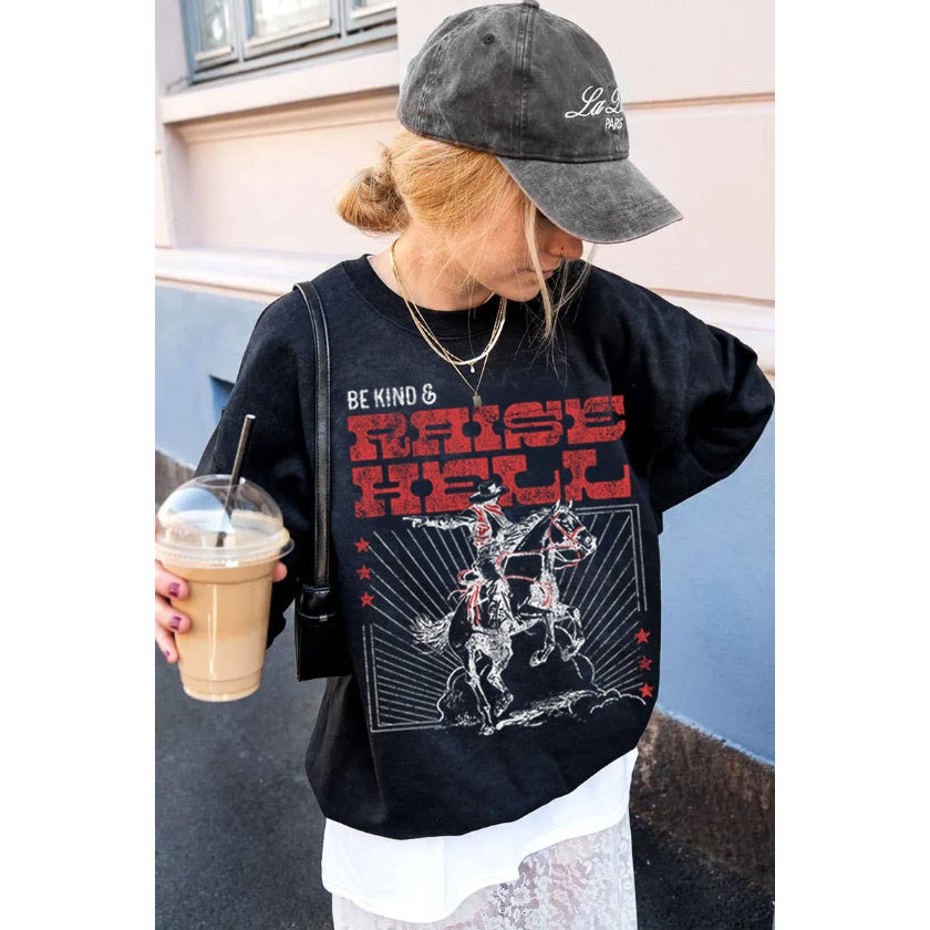 Person wearing a black sweatshirt with graphic design and text, holding a drink.