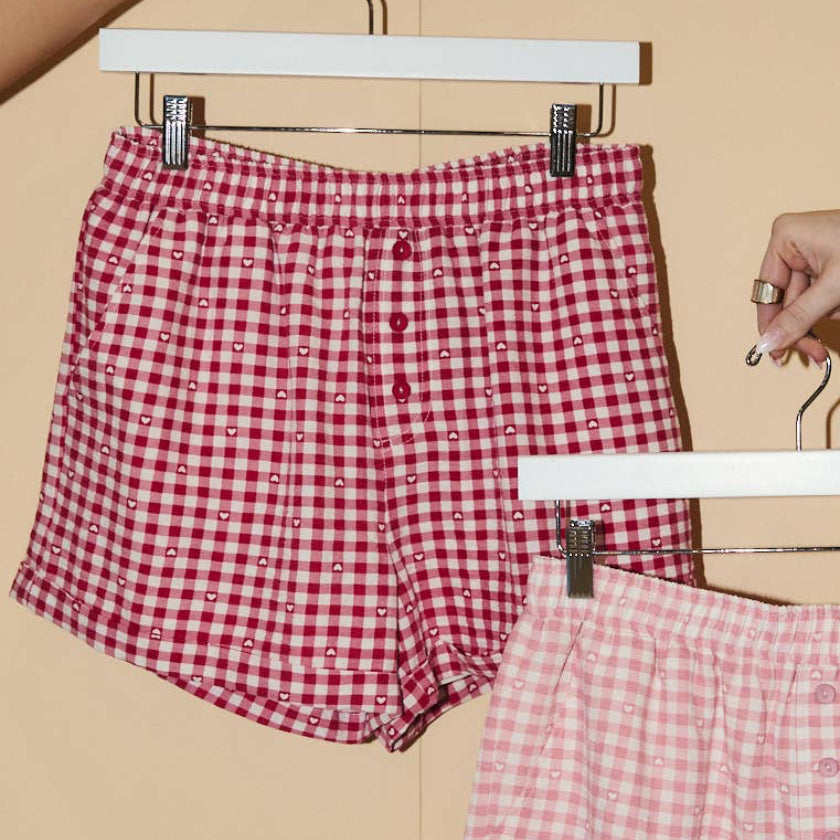 Red and pink checkered shorts on hangers against a beige background