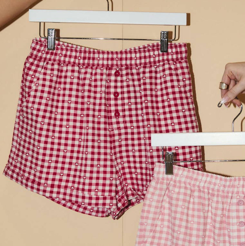 Red and pink checkered shorts on hangers against a beige background