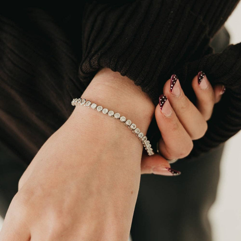 Hand wearing a silver bracelet with a blurred background