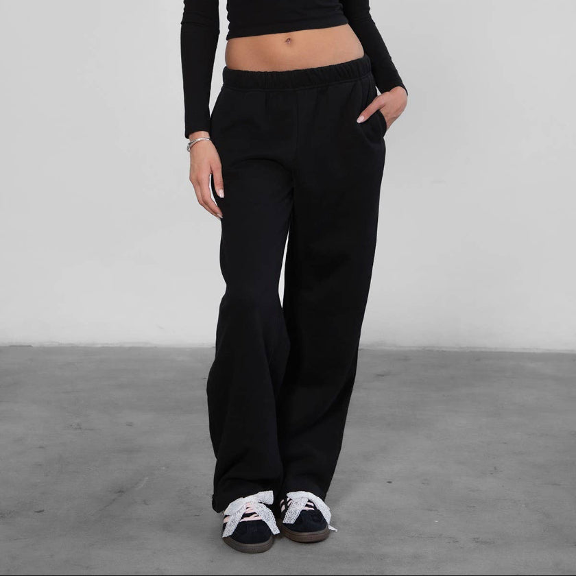 Person wearing a black long-sleeve top and black pants against a plain background