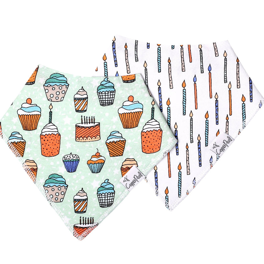 Two baby bibs with cake and cupcake patterns on a white background