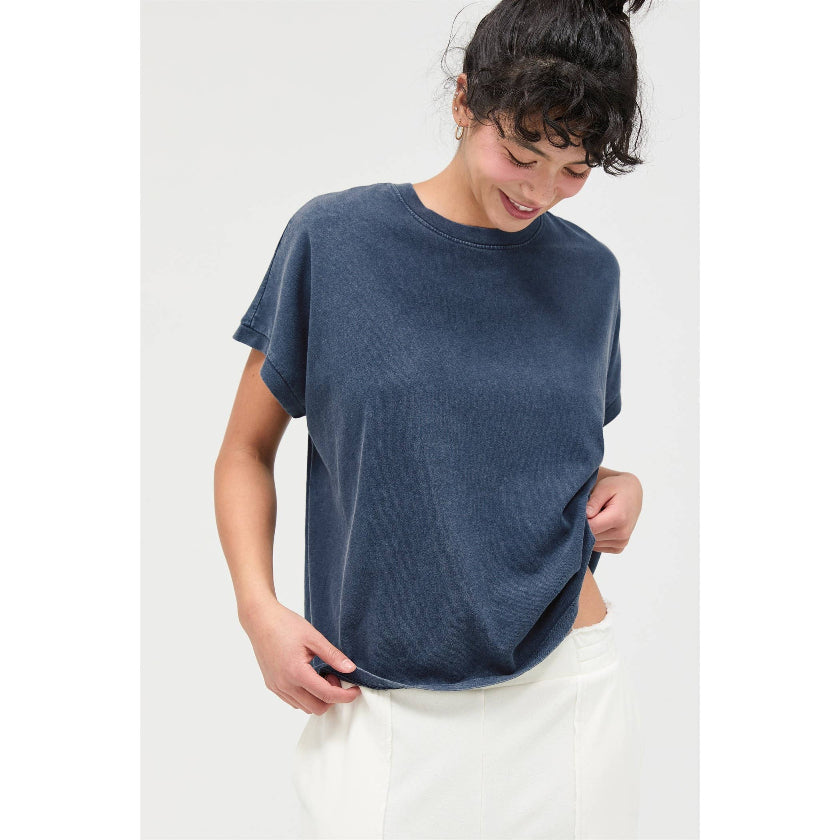 Person wearing a blue t-shirt and white pants against a white background