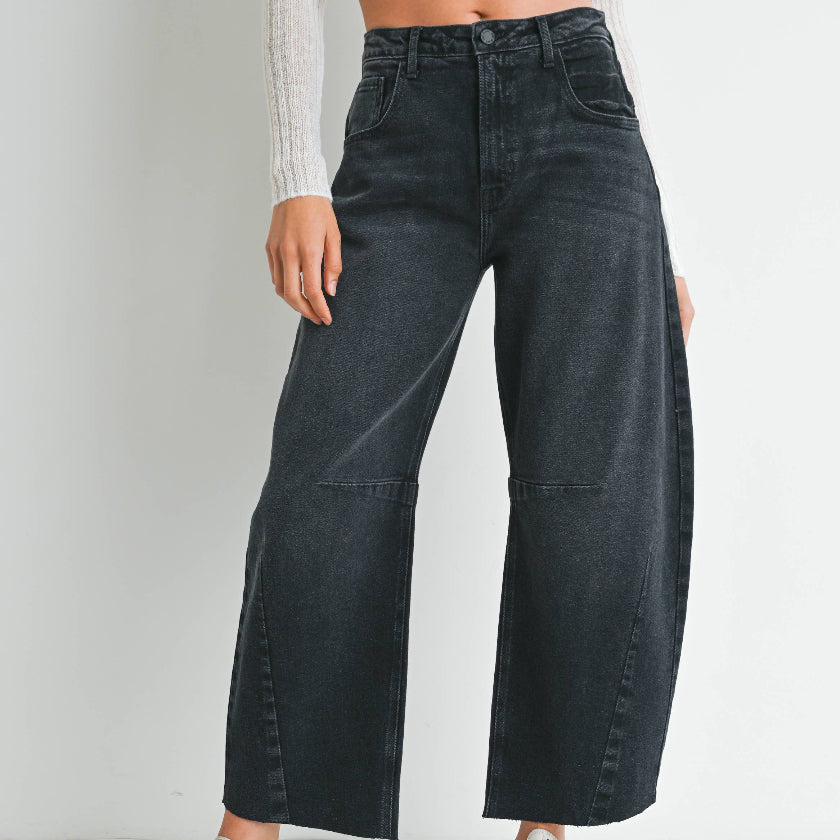 Person wearing black wide-leg jeans with a white background