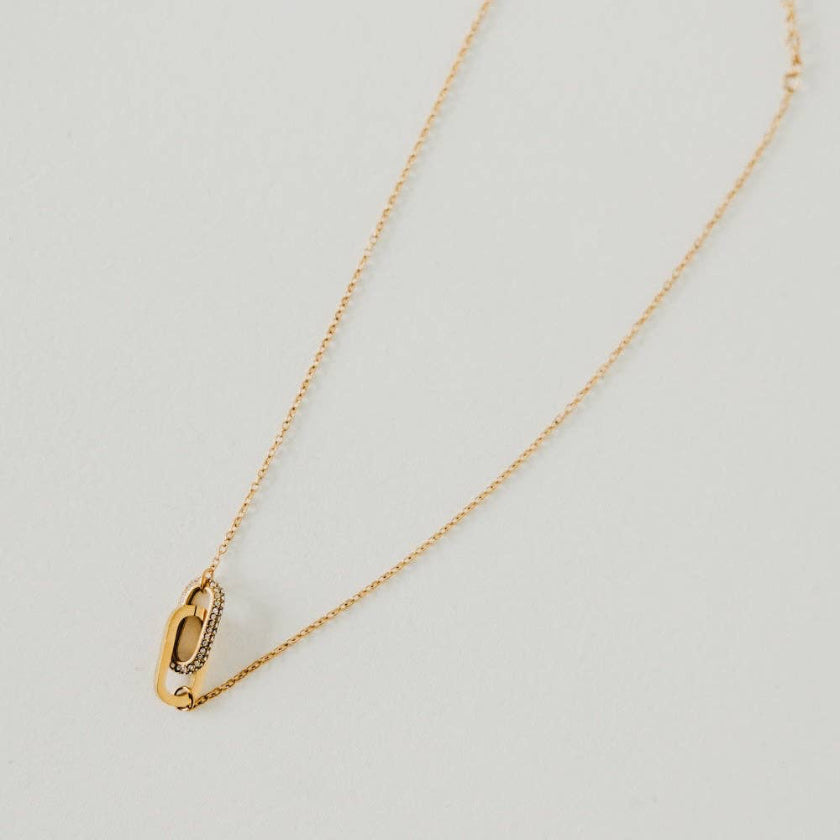 Gold necklace with a unique pendant on a light gray background