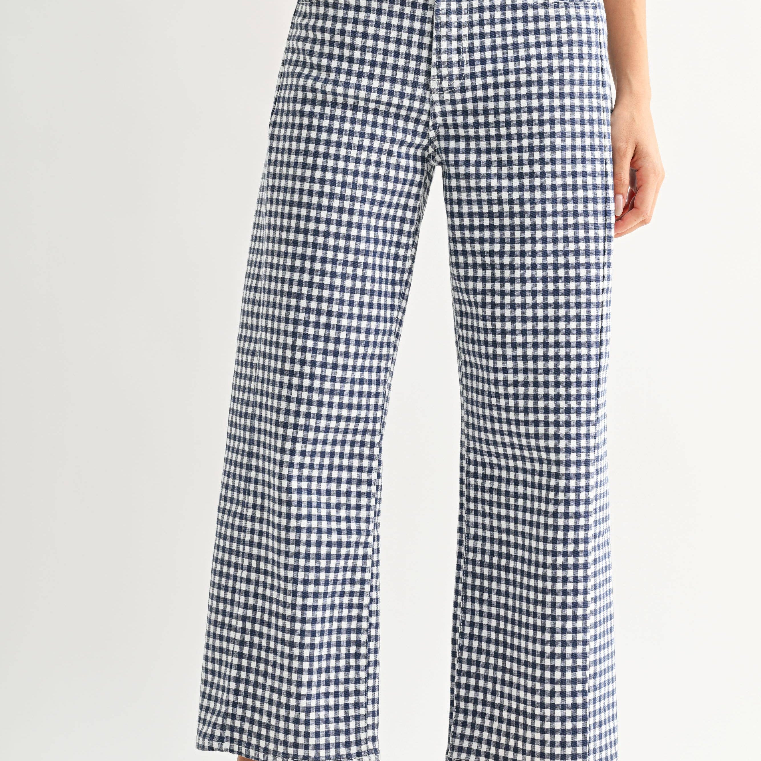 Person wearing blue and white checkered pants with red shoes on a light gray background