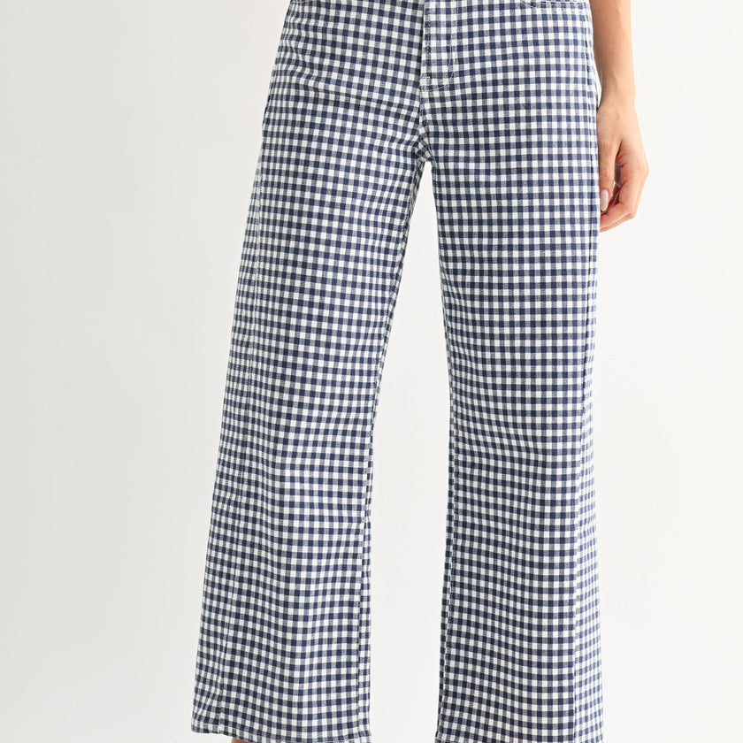 Person wearing blue and white checkered pants with red shoes on a light gray background