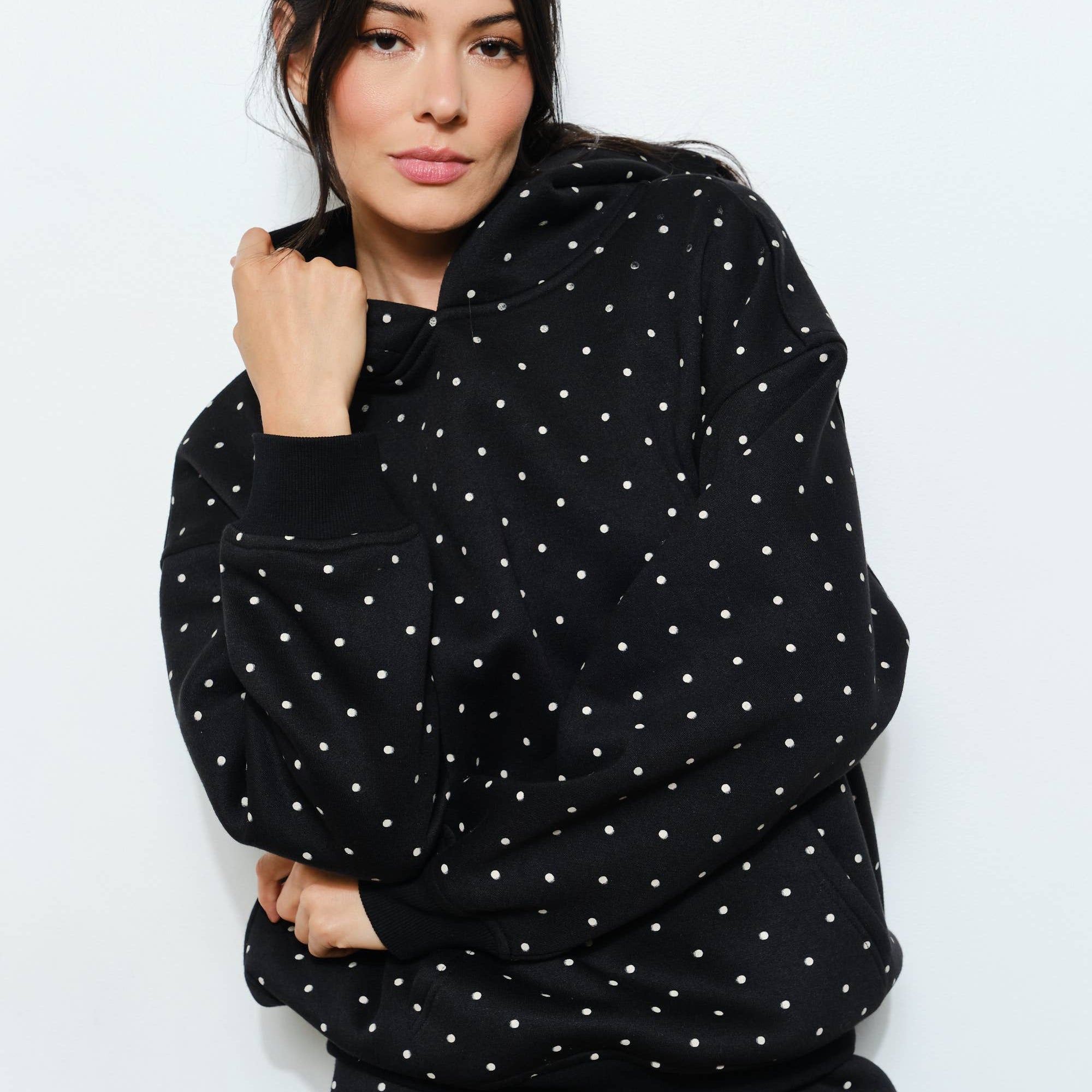 Woman wearing a black polka dot hoodie and shorts set on a white background