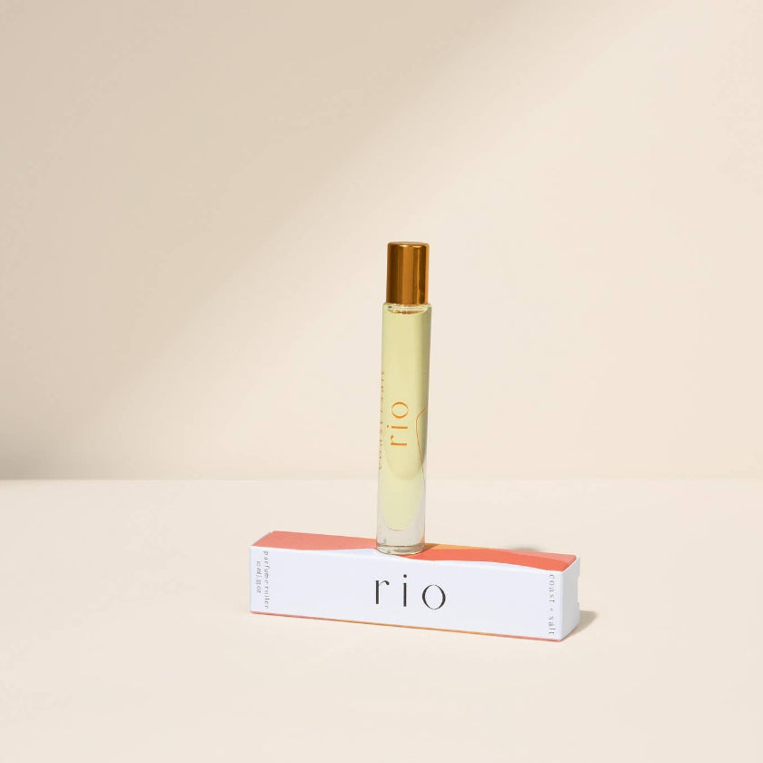 Roll-on perfume bottle with red cap and white label on a beige background