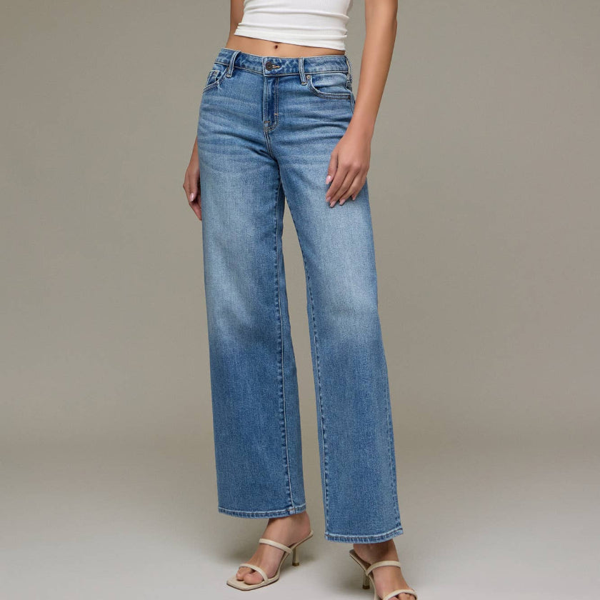 Woman wearing a white halter top and blue jeans against a neutral background