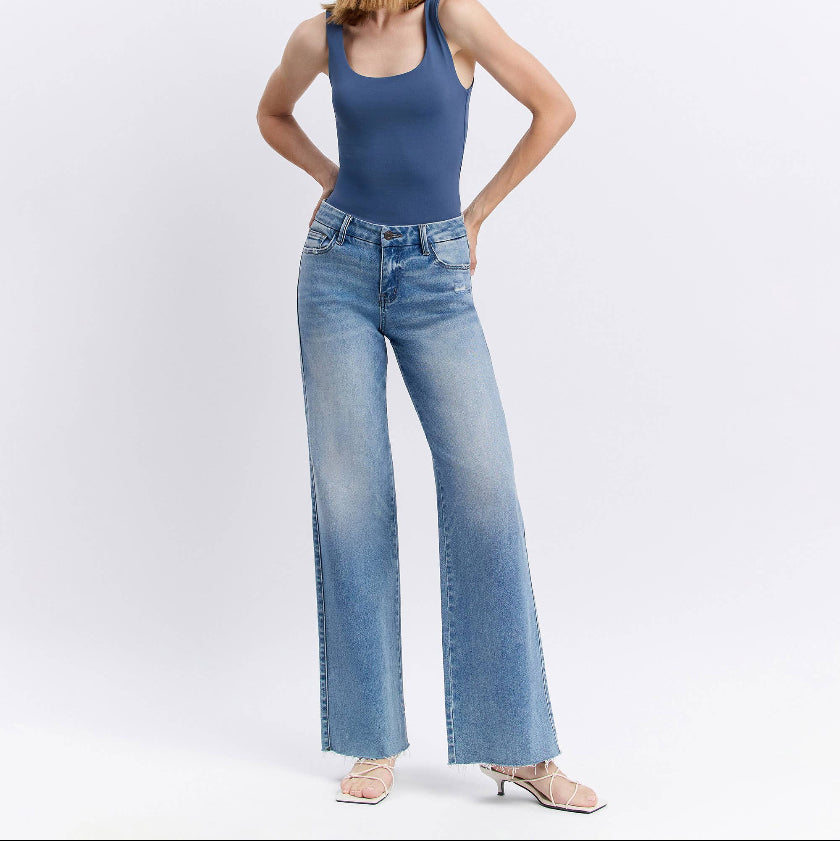 Woman wearing a blue tank top and light blue jeans on a white background