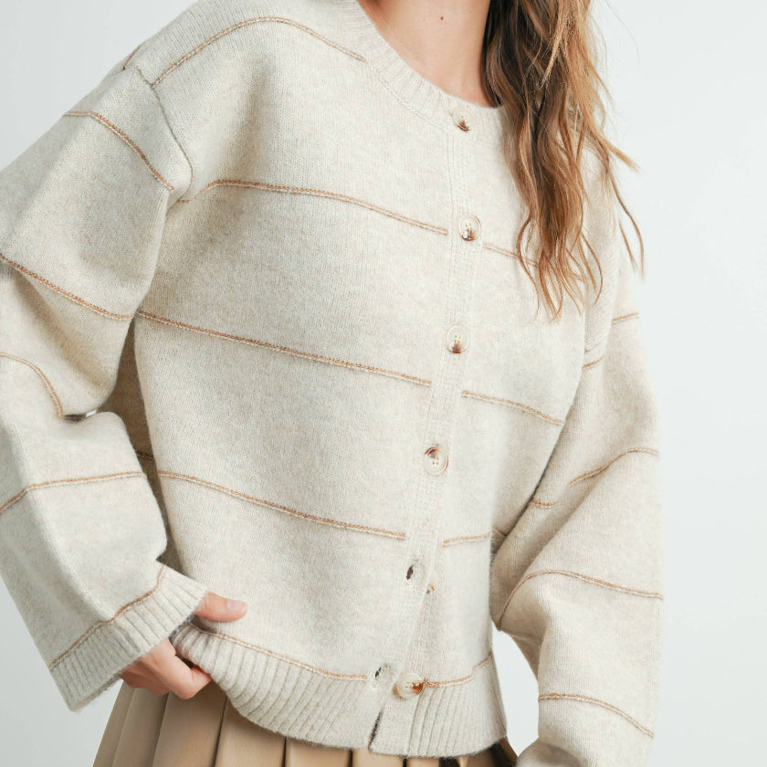 Woman wearing a beige cardigan with a white background