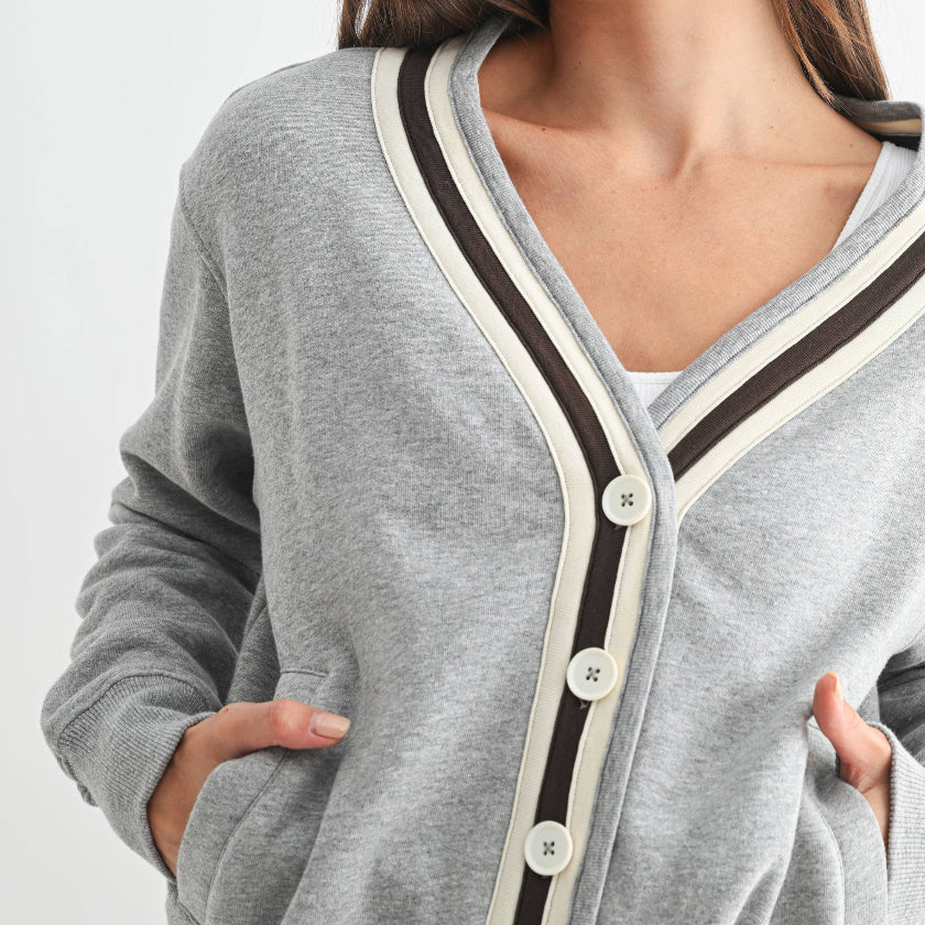 Woman wearing a gray cardigan with black and white trim on a light gray background