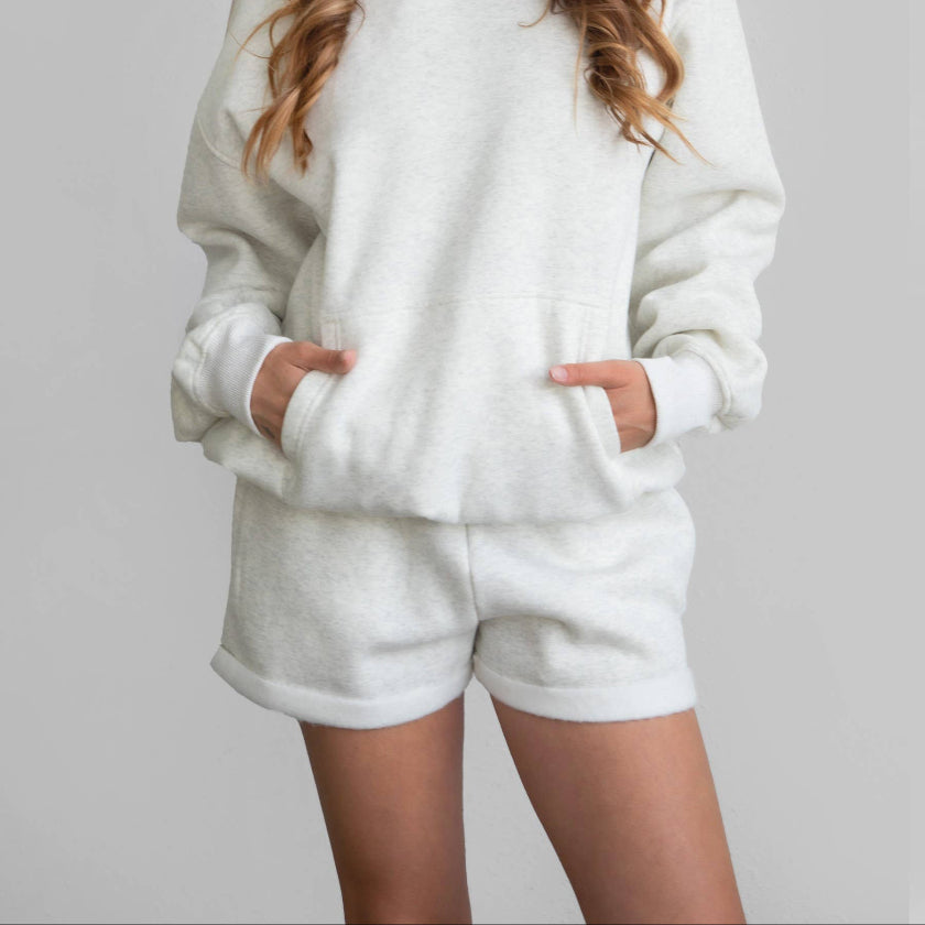 Woman wearing a white hoodie and shorts set on a gray background