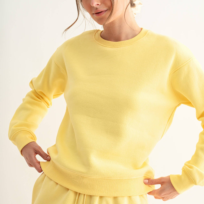 Woman wearing a yellow sweatshirt and shorts set on a white background