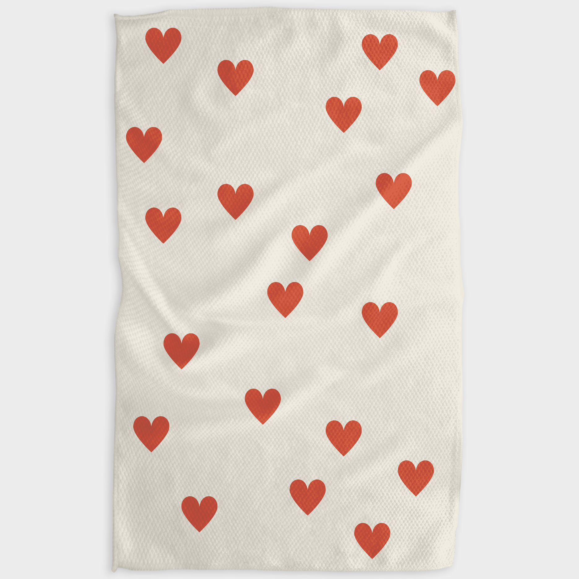 Beige towel with red heart pattern on a white background