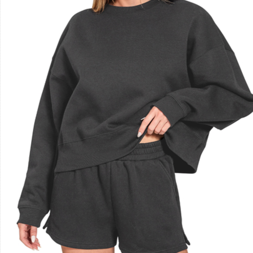 Person wearing a dark gray sweatshirt and shorts set on a white background