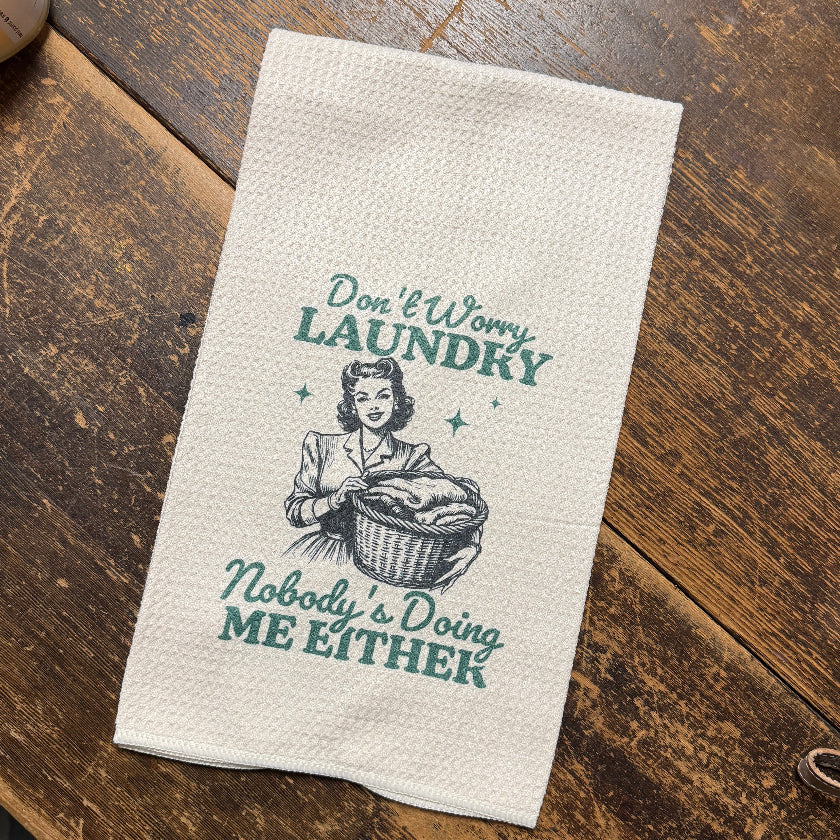Fabric towel with vintage-style laundry design on a wooden surface