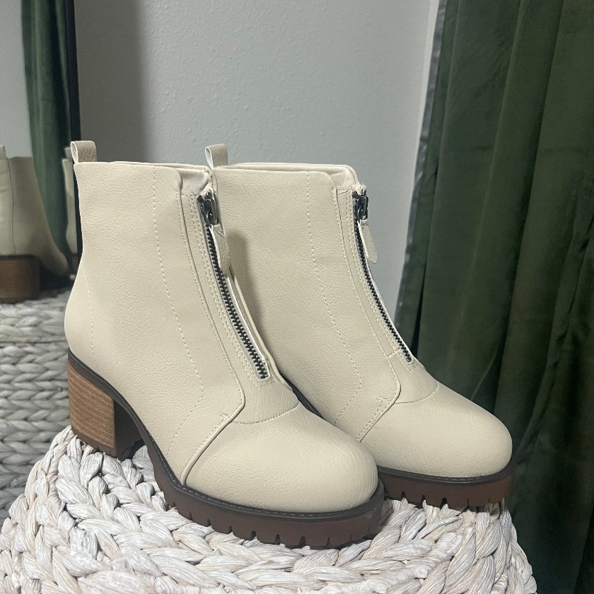 Pair of beige ankle boots with zippers on a woven surface