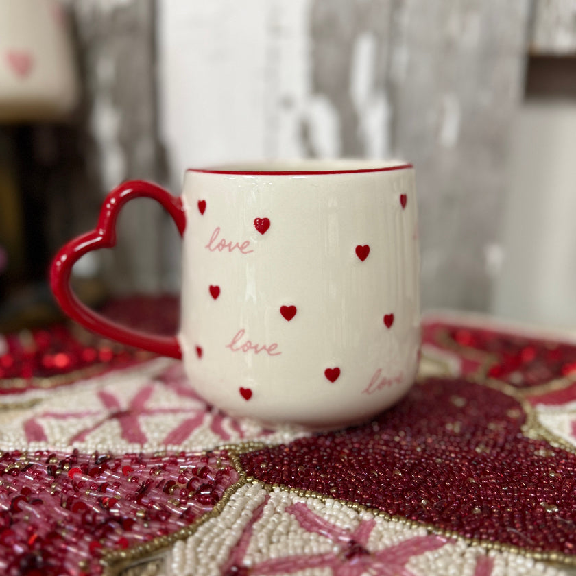 White mug with red hearts and 'love' text on a decorative surface