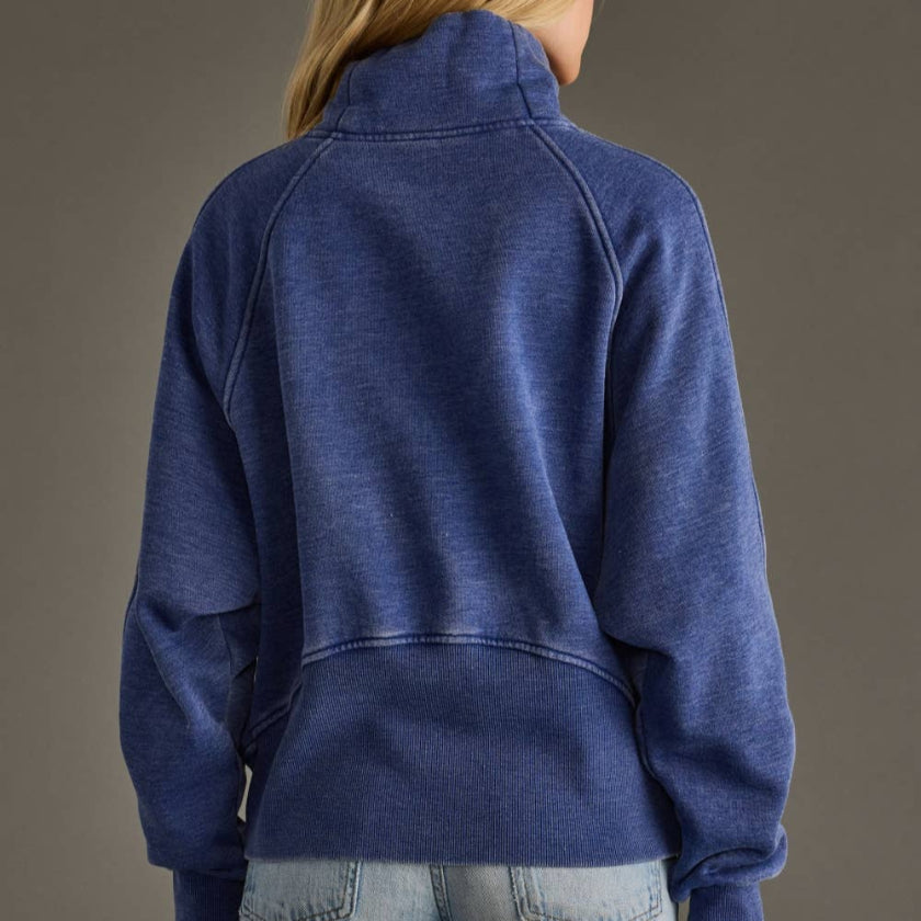 Person wearing a blue pullover against a gray background