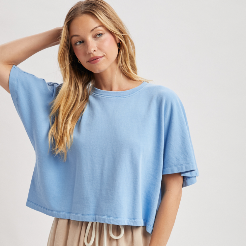 Woman wearing a light blue oversized t-shirt and beige shorts on a white background