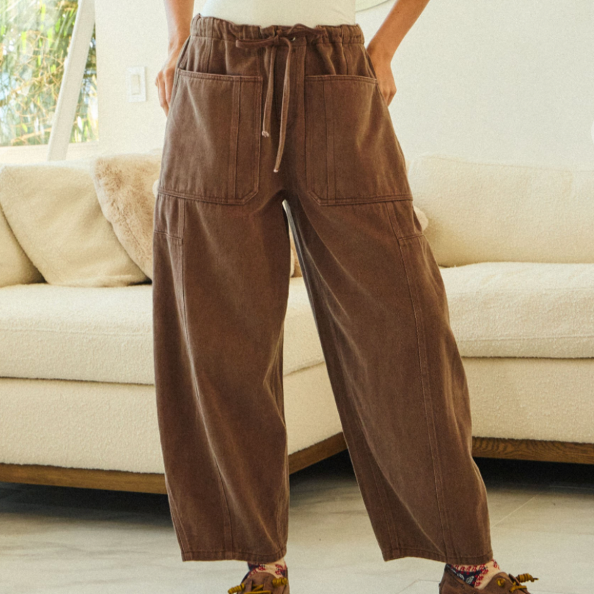 Person wearing brown wide-leg pants and a white top in a living room setting.
