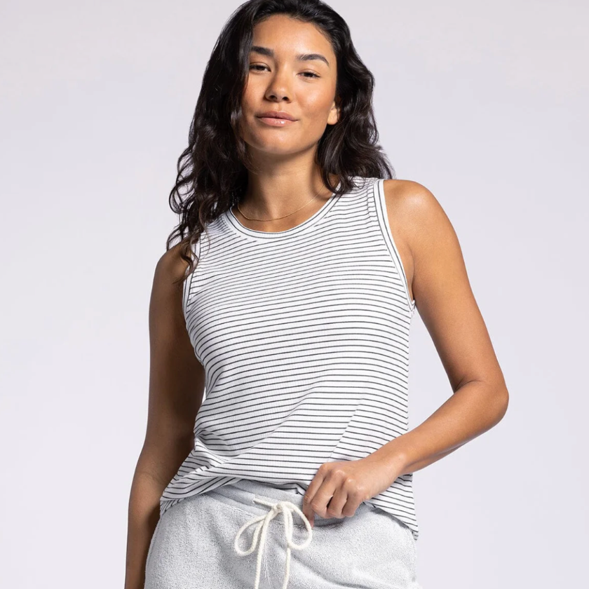 Woman wearing a striped tank top and gray sweatpants on a white background