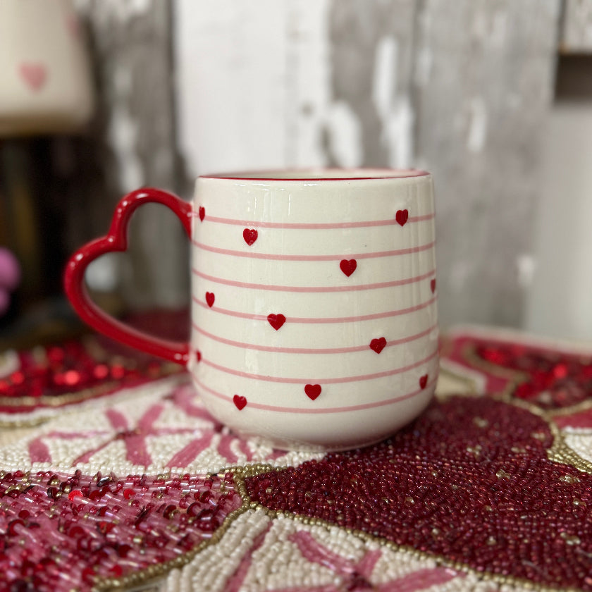 White mug with red heart patterns on a textured surface