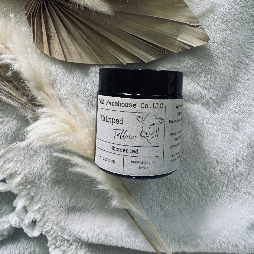 Jar of whipped talcum on a textured surface with dried leaves and feathers