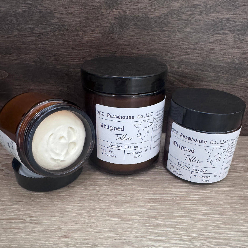 Three tallow products from Old Farmhouse Co. on a wooden surface.