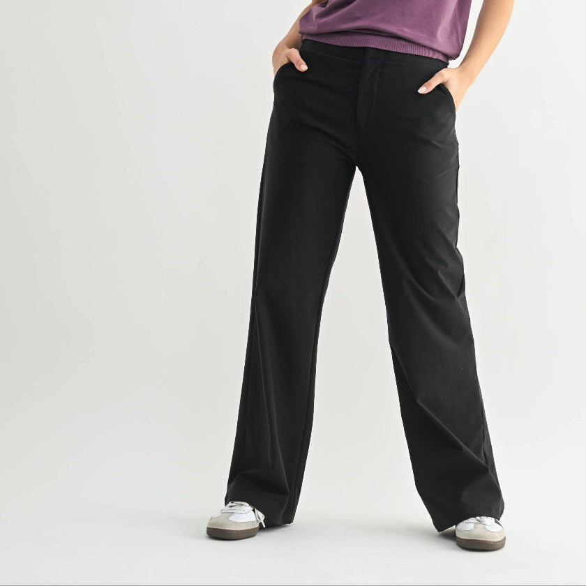 Woman wearing a purple top and black pants on a white background