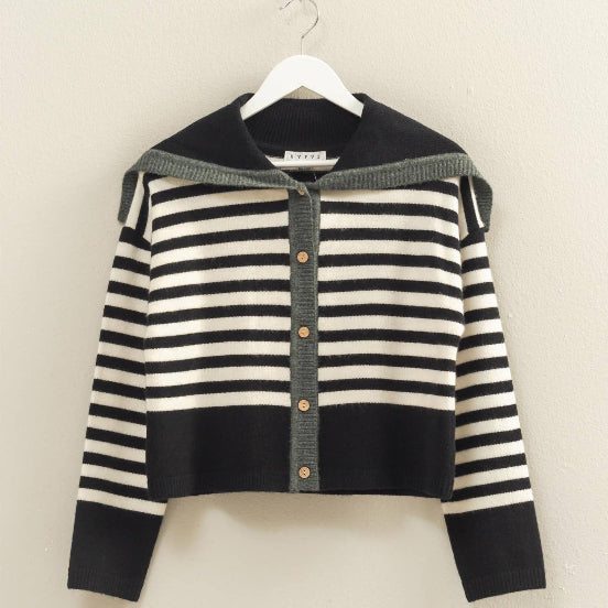 Black and white striped sweater on a hanger against a beige background