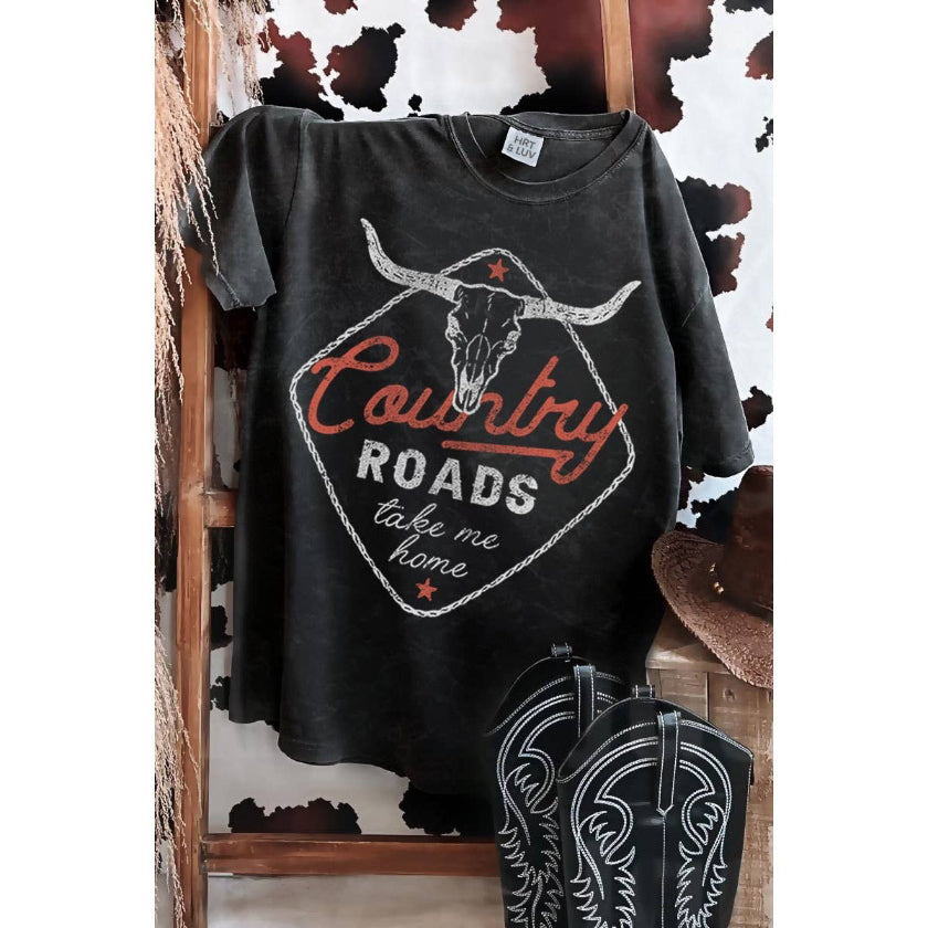 Black t-shirt with 'Country Roads take me home' design on a wooden stand with cowboy boots and hat.
