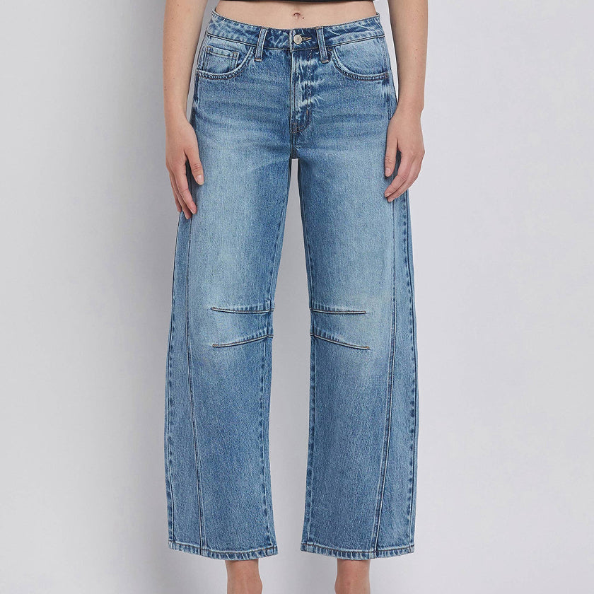 Person wearing blue jeans on a plain background