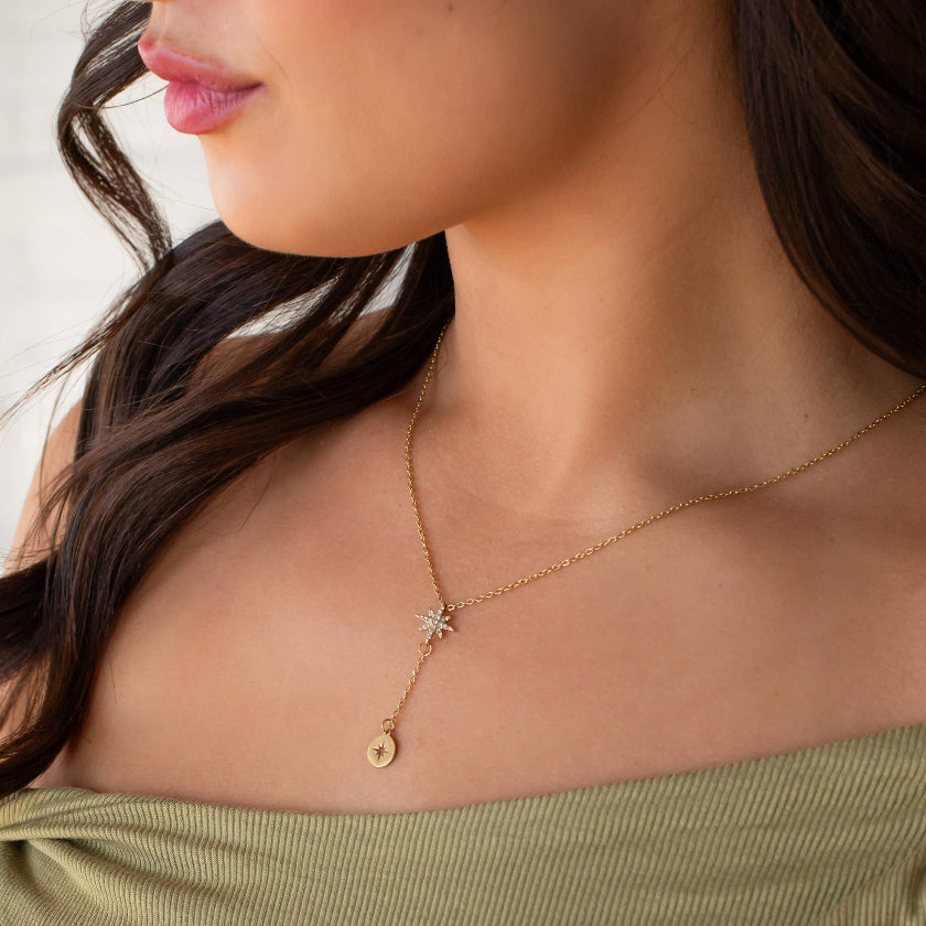 Close-up of a woman wearing a gold necklace with a star pendant.