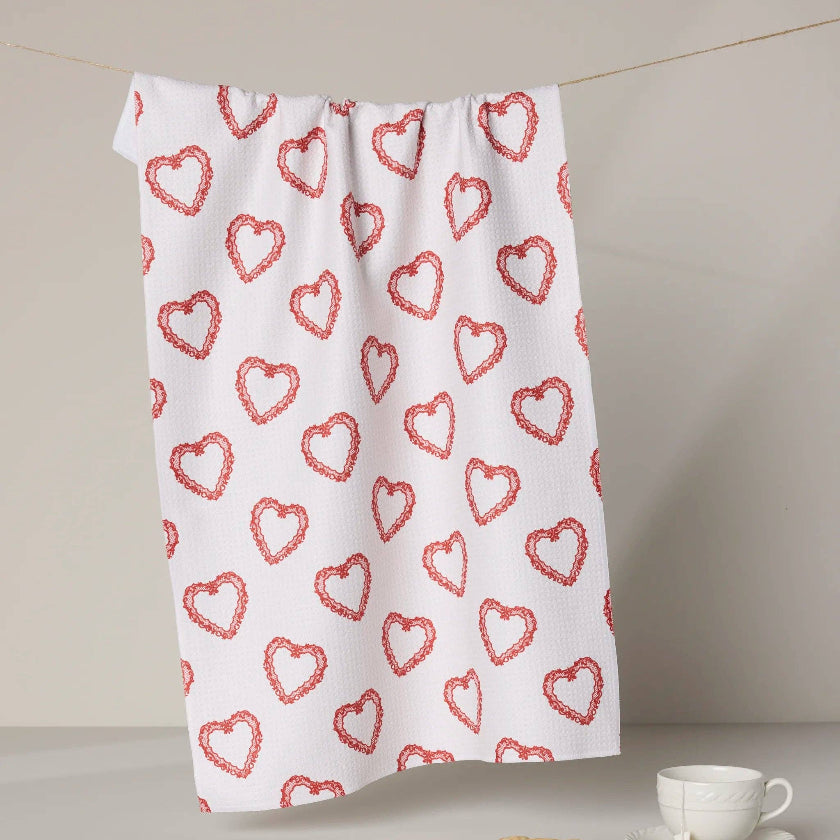 White towel with red heart pattern on a neutral background
