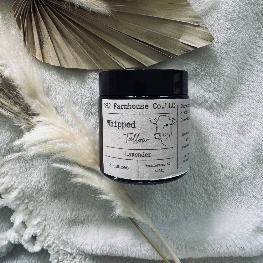 Candle jar labeled 'Farmhouse Co., LLC' on a textured surface with dried plants.