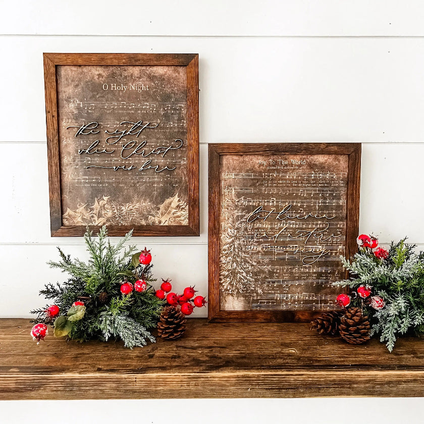 Two wooden framed signs with Christmas decorations on a mantel.