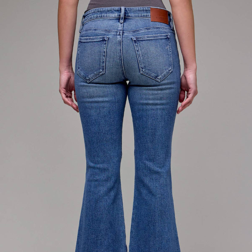 Blue flared jeans worn by a person on a plain background