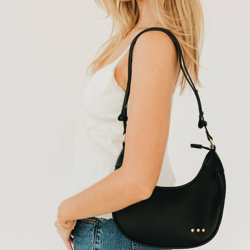 Person wearing a black shoulder bag on a plain background